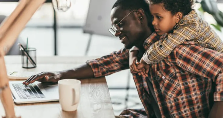 Dad and son at a desk looking at a laptop